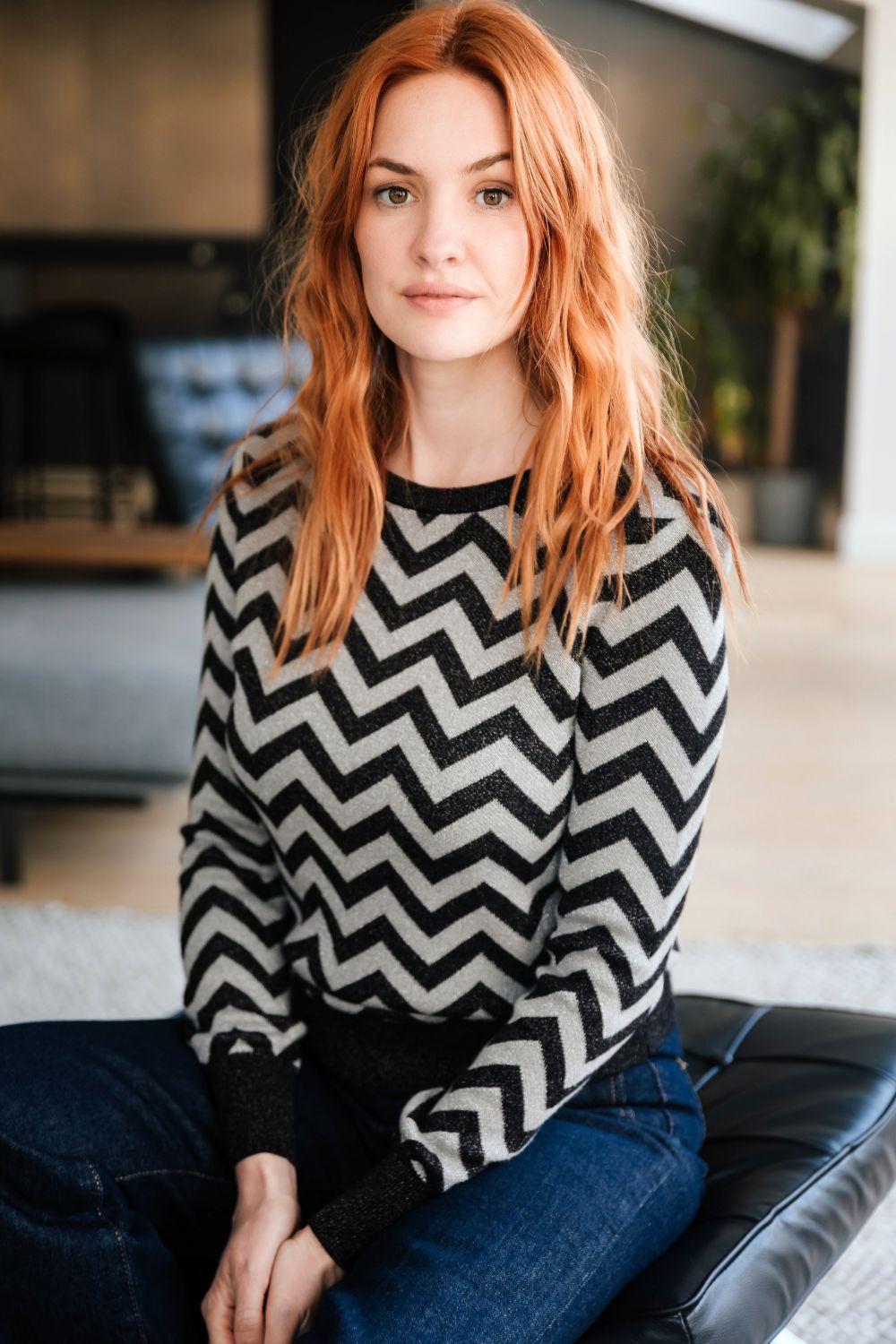 Person wearing a black and white zigzag patterned sweater sitting on a couch.