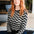 Person wearing a black and white zigzag patterned sweater sitting on a couch.