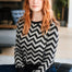 Person wearing a black and white zigzag patterned sweater sitting on a couch.