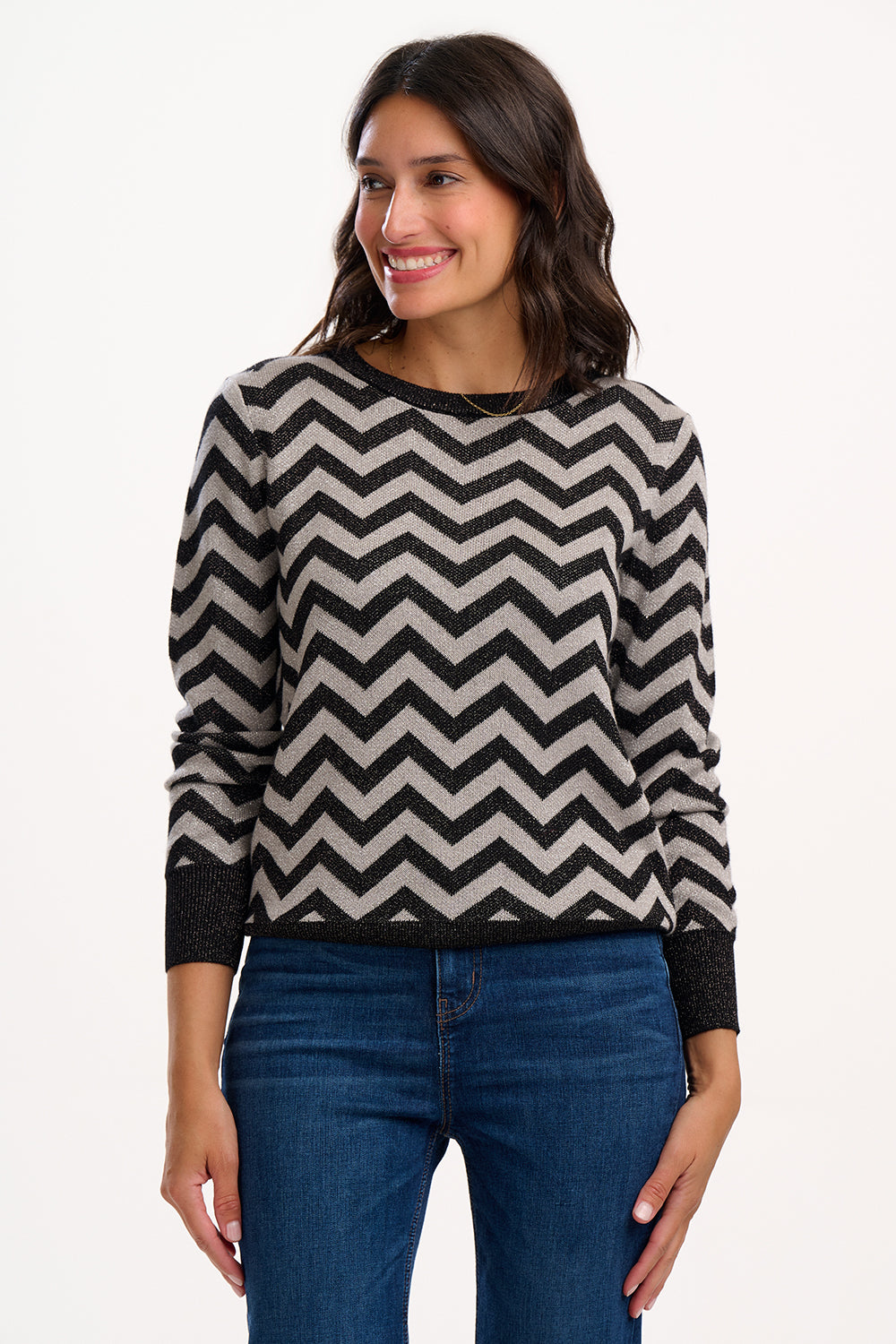Woman wearing a black and beige zigzag patterned sweater on a white background