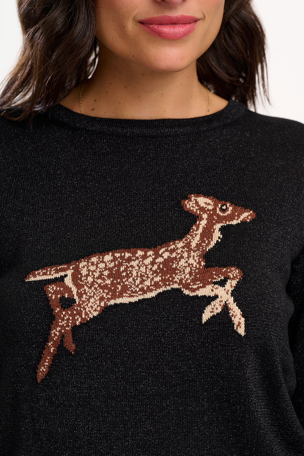 Black sweater with a brown deer design worn by a person