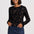 A woman modeling a black long-sleeve knit top with a brown leopard print pattern, paired with a blue denim mini skirt, against a light gray studio background.