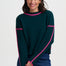 Woman wearing a dark green sweater with pink accents on a white background