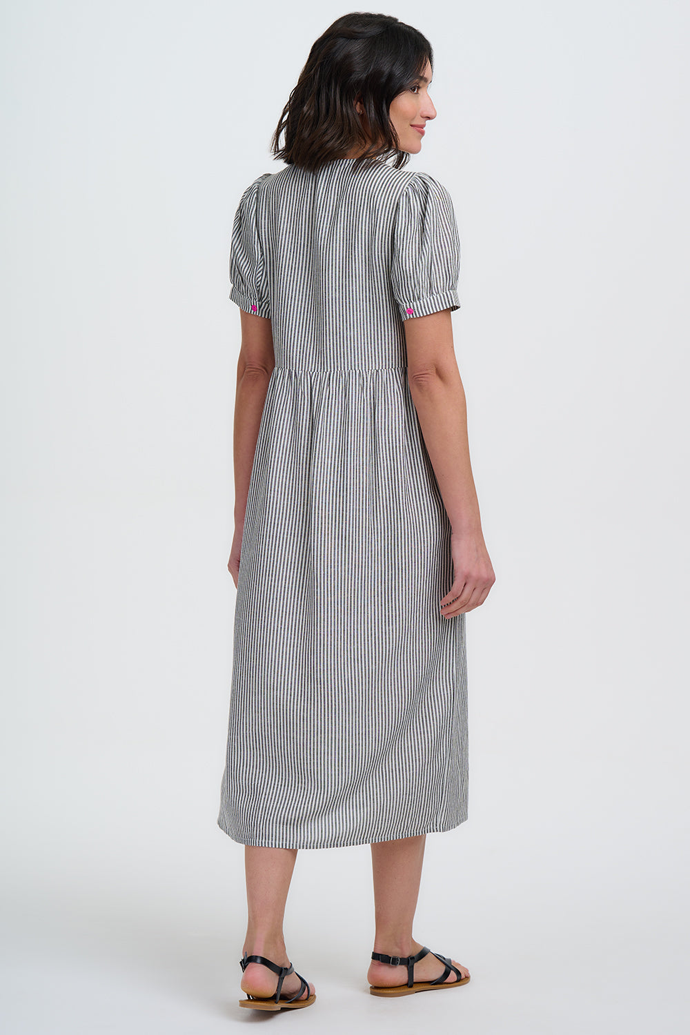 Woman wearing a gray and white striped dress on a white background