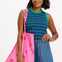 A woman wearing a sleeveless fitted vest top with blue and green stripes, paired with denim shorts and carrying a pink bag with stars.