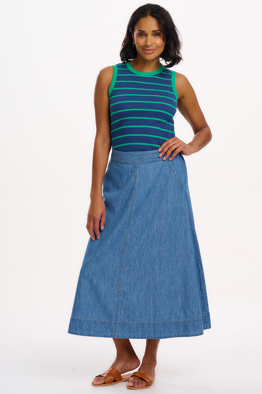 A woman wearing a sleeveless fitted vest top with blue and green horizontal stripes.
