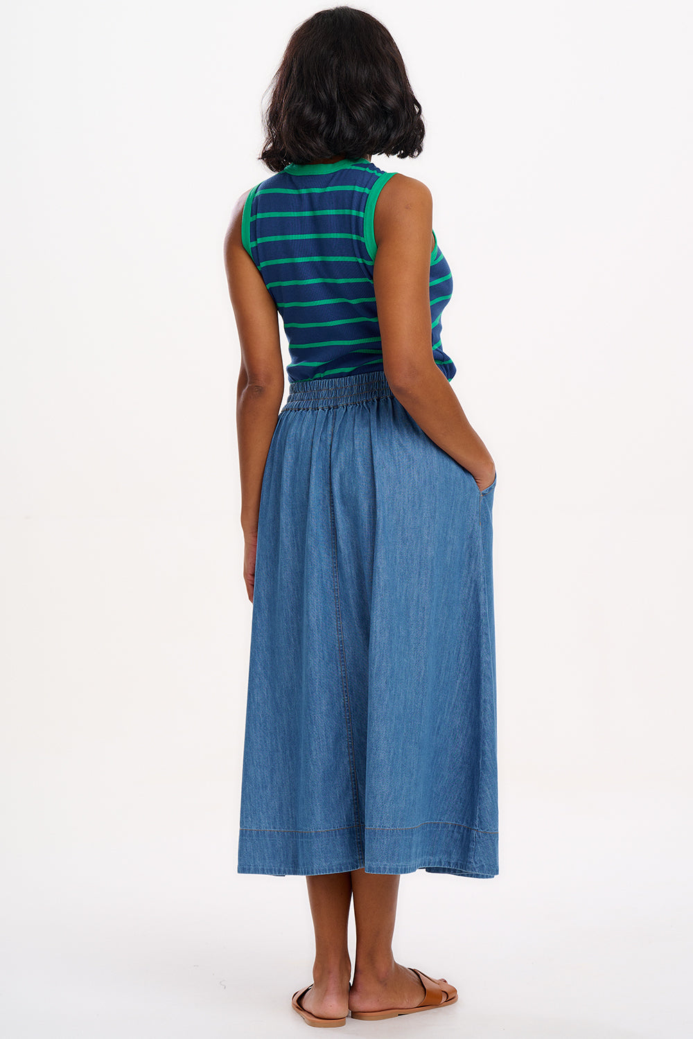 A woman wearing a sleeveless fitted vest top with blue and green horizontal stripes.