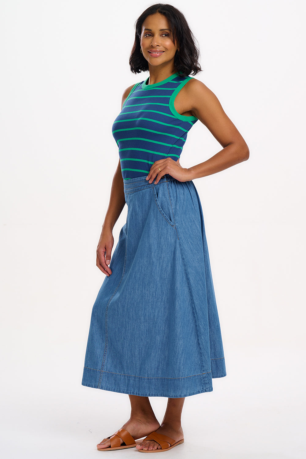A woman wearing a sleeveless fitted vest top with blue and green horizontal stripes.