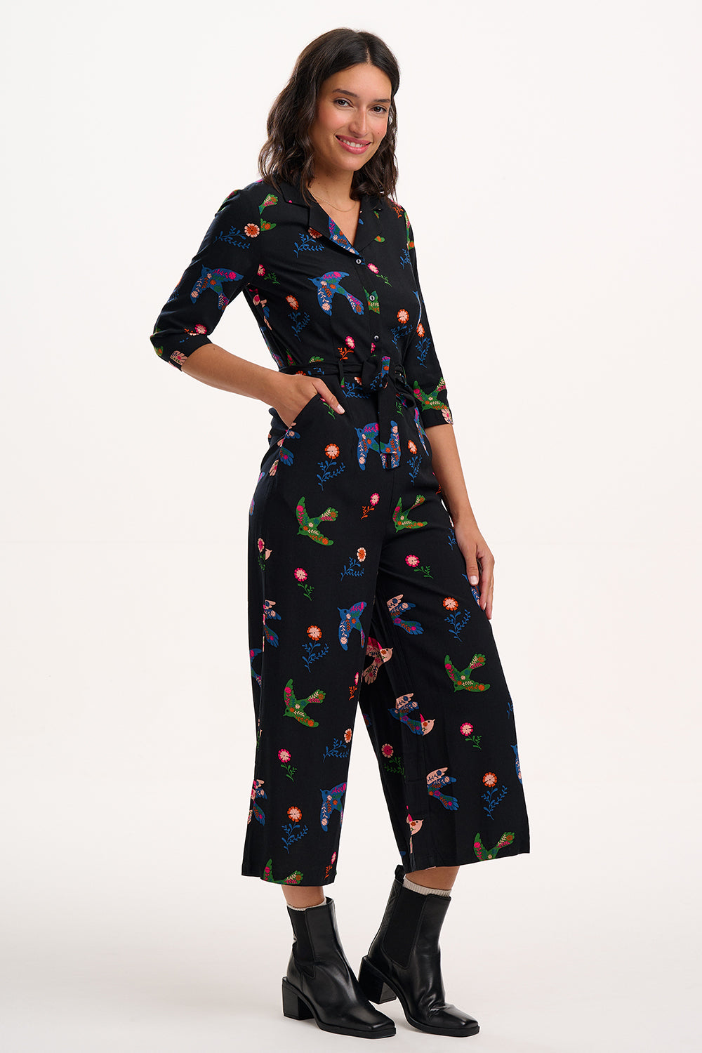 Woman wearing a black jumpsuit with colorful patterns on a white background