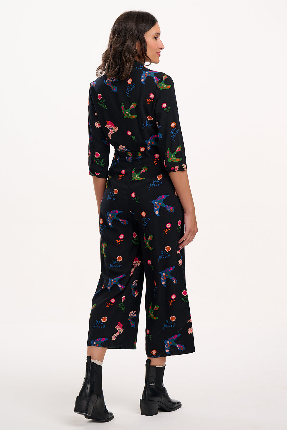 Woman wearing a black floral jumpsuit on a white background