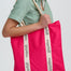 Person holding a pink tote bag with 'sugarhill' branding on a white background