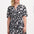 A woman wearing a knee-length V-neck dress with short sleeves and a tiered skirt. The dress features a black and white floral folk print.