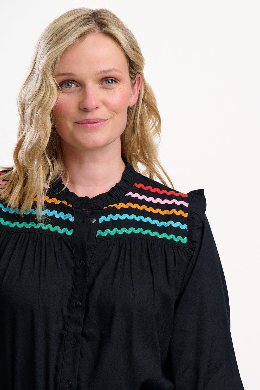 Woman wearing a black blouse with colorful embroidery on a white background