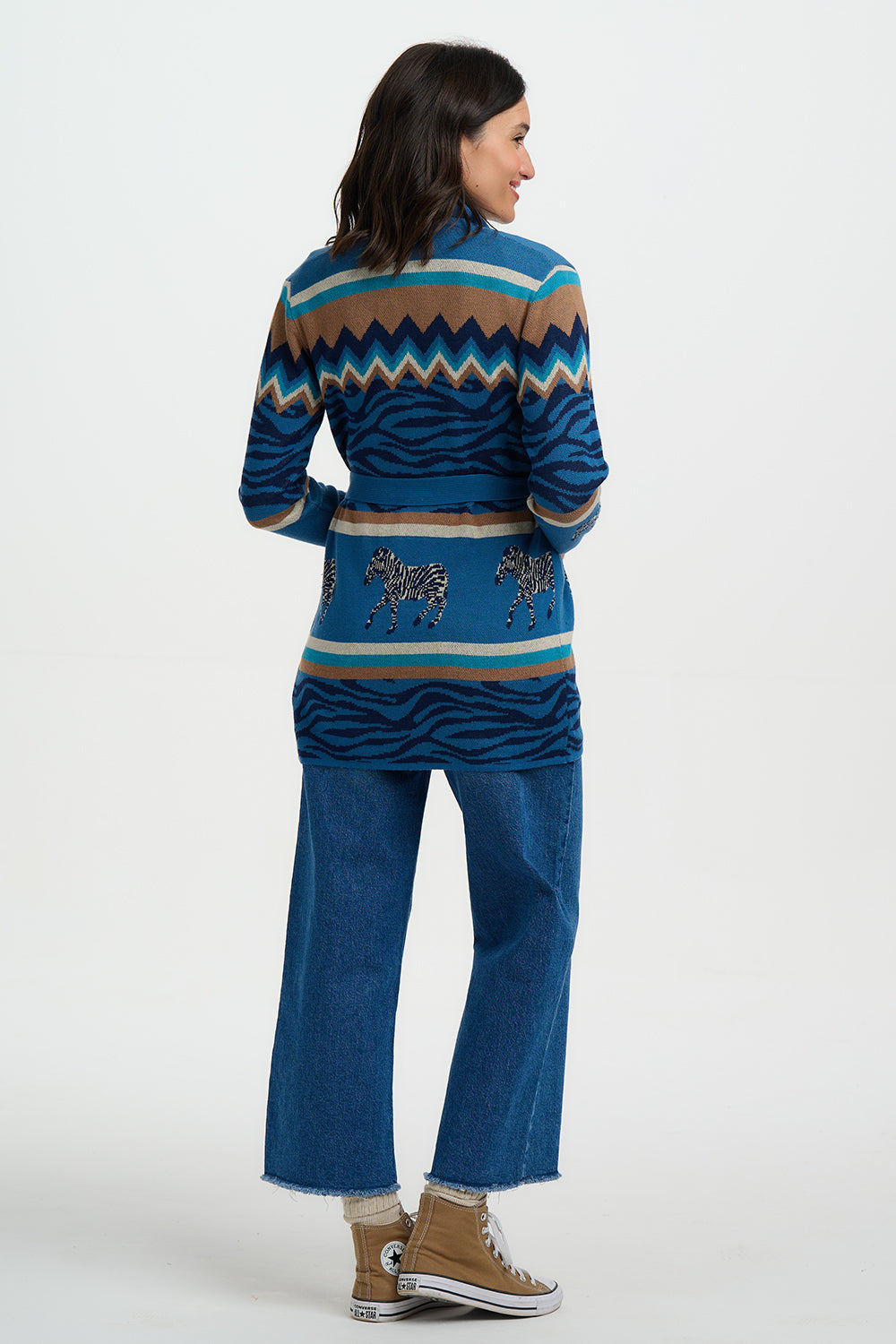 Woman wearing a blue patterned sweater and jeans on a white background