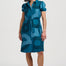 Woman wearing a blue dress with black patterns on a white background