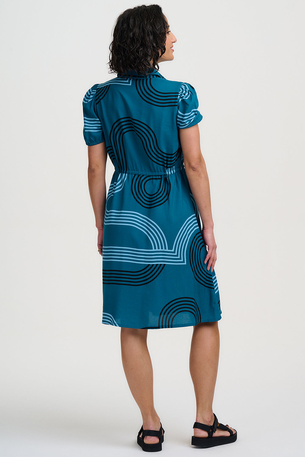 Woman wearing a blue dress with black and white pattern on a white background