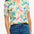 A woman wearing an off-white Santana shirt with a colorful jungle print, featuring short sleeves and a revere collar.