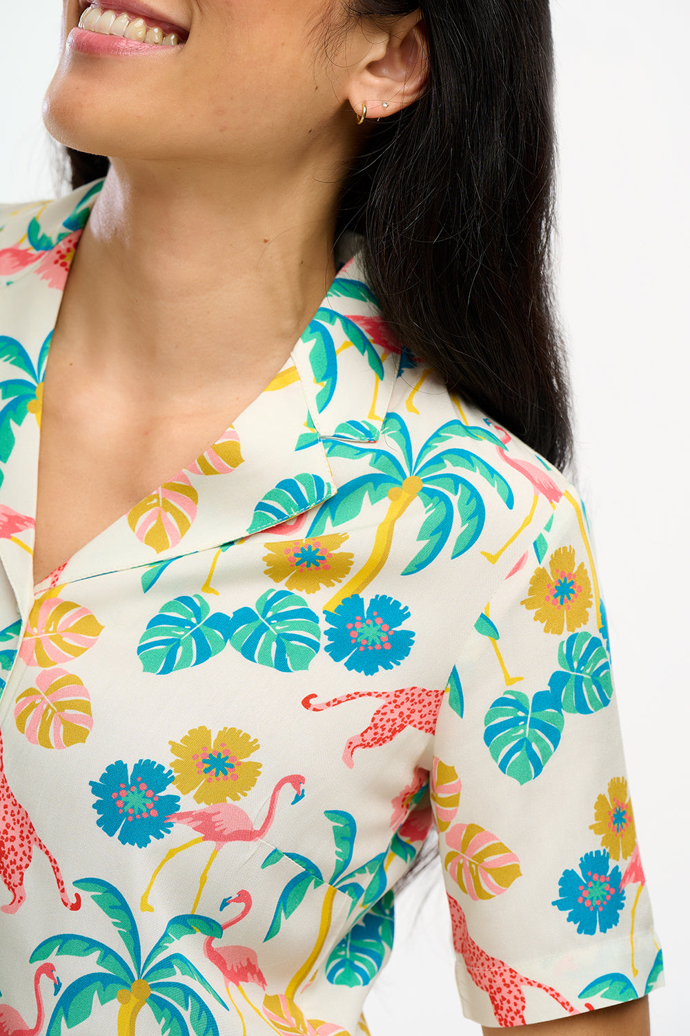 A woman wearing an off-white Santana shirt with a colorful jungle print, featuring short sleeves and a revere collar.