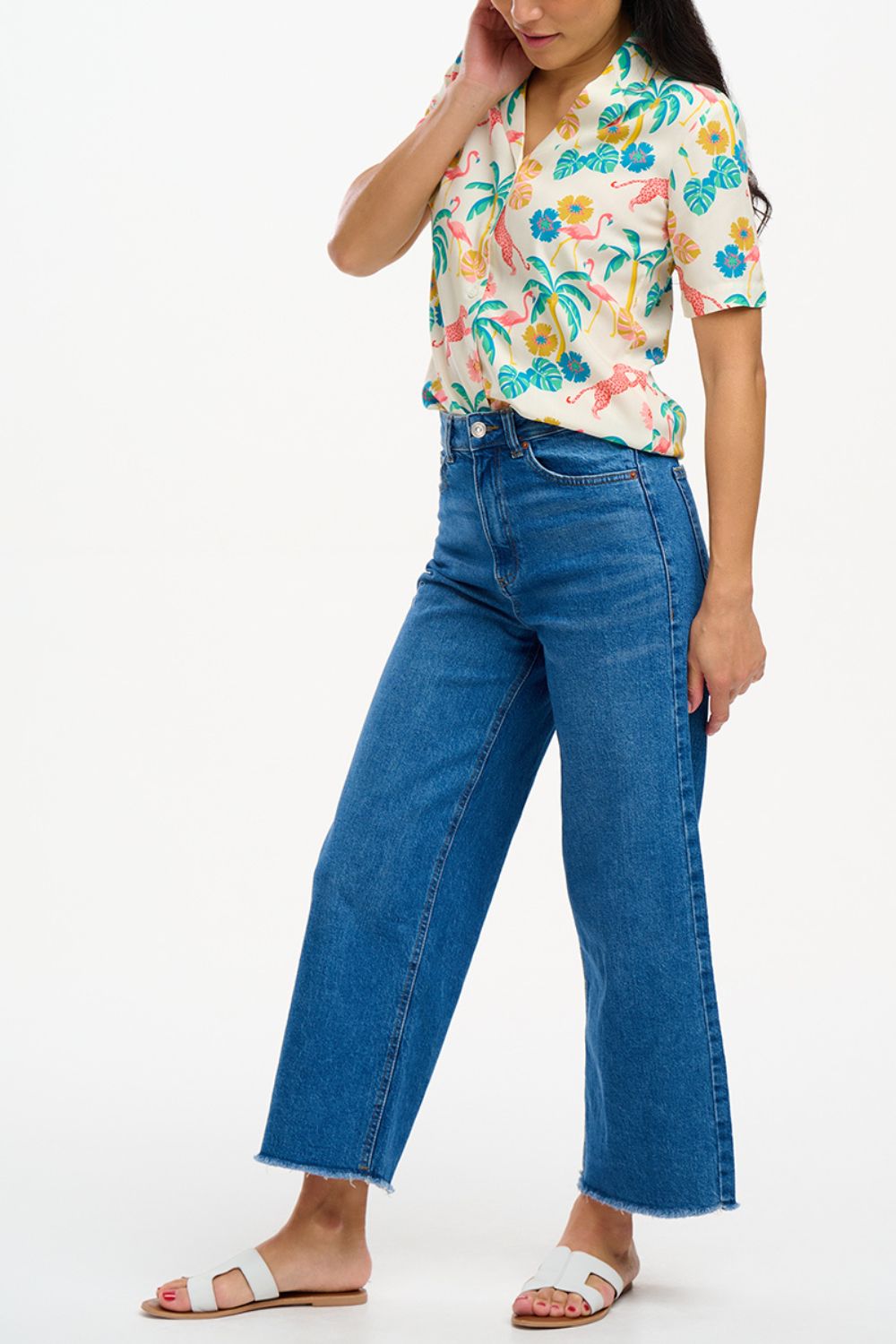 A woman wearing an off-white Santana shirt with a colorful jungle print, featuring short sleeves and a revere collar.