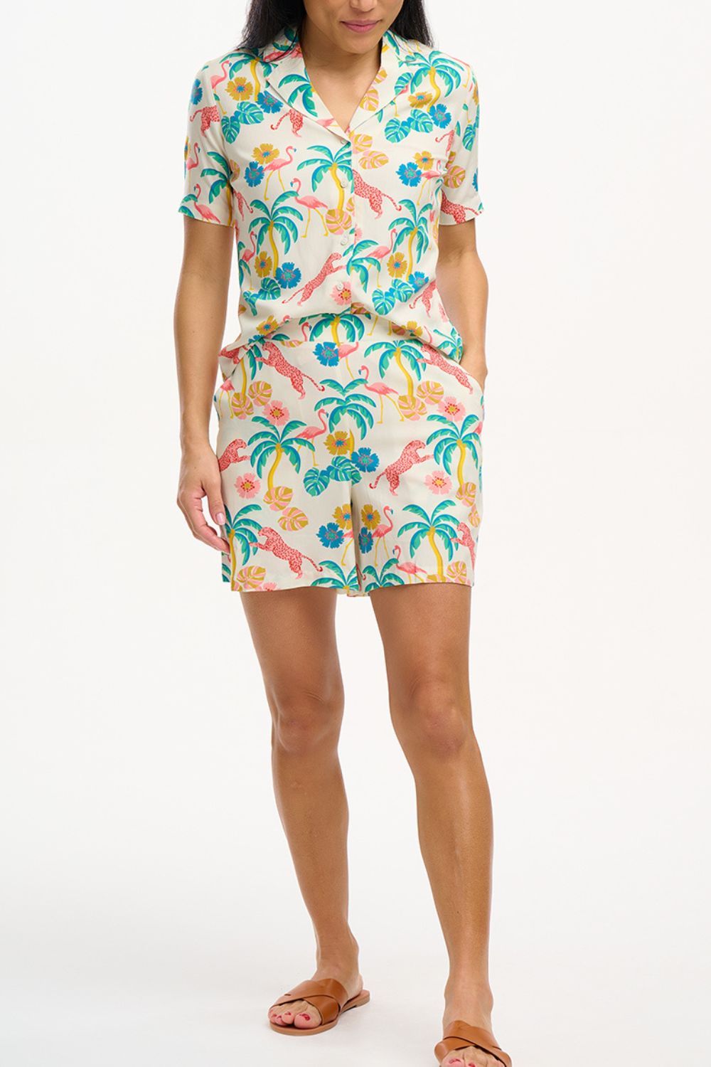 A woman wearing an off-white Santana shirt with a colorful jungle print, featuring short sleeves and a revere collar.