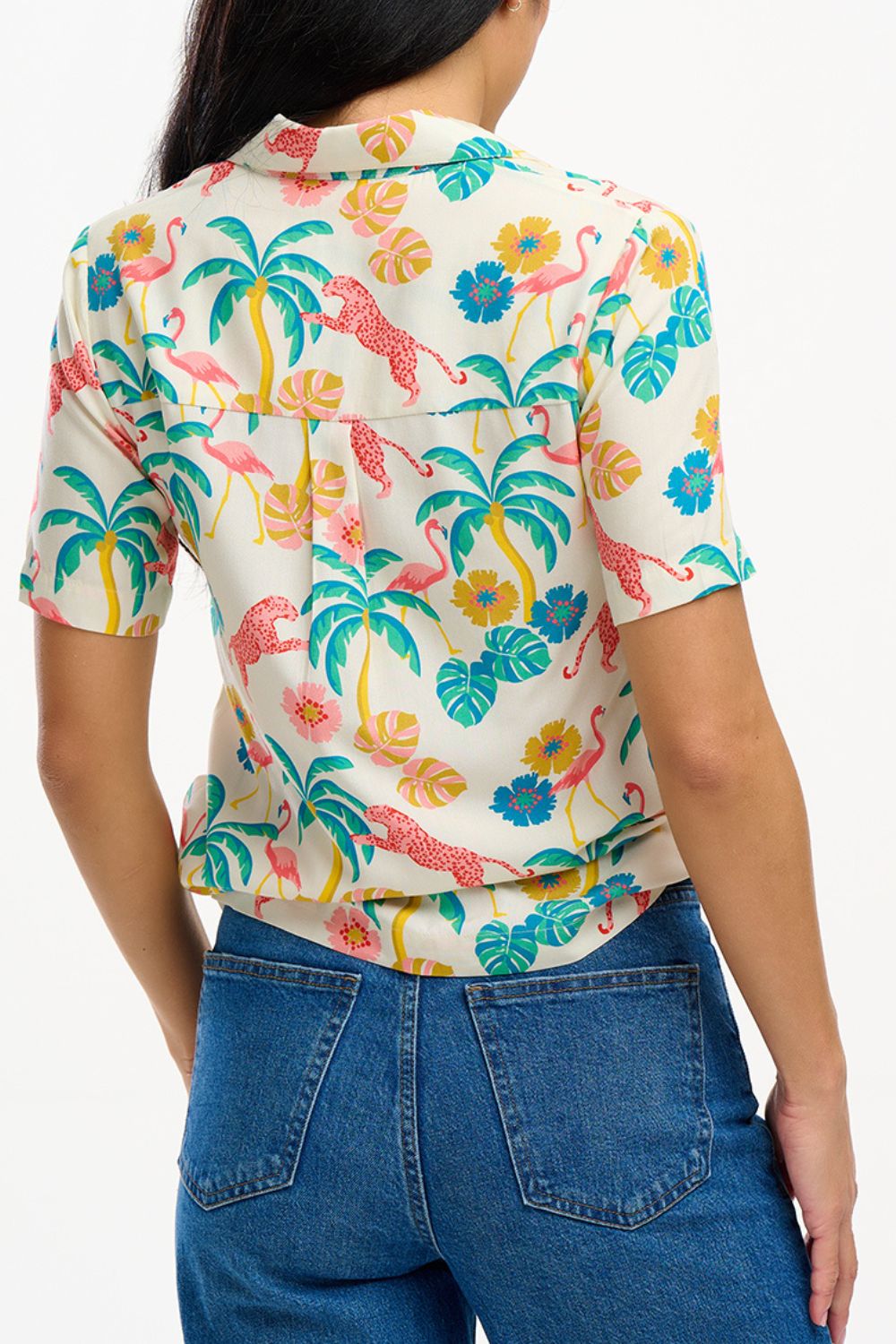 A woman wearing an off-white Santana shirt with a colorful jungle print, featuring short sleeves and a revere collar.