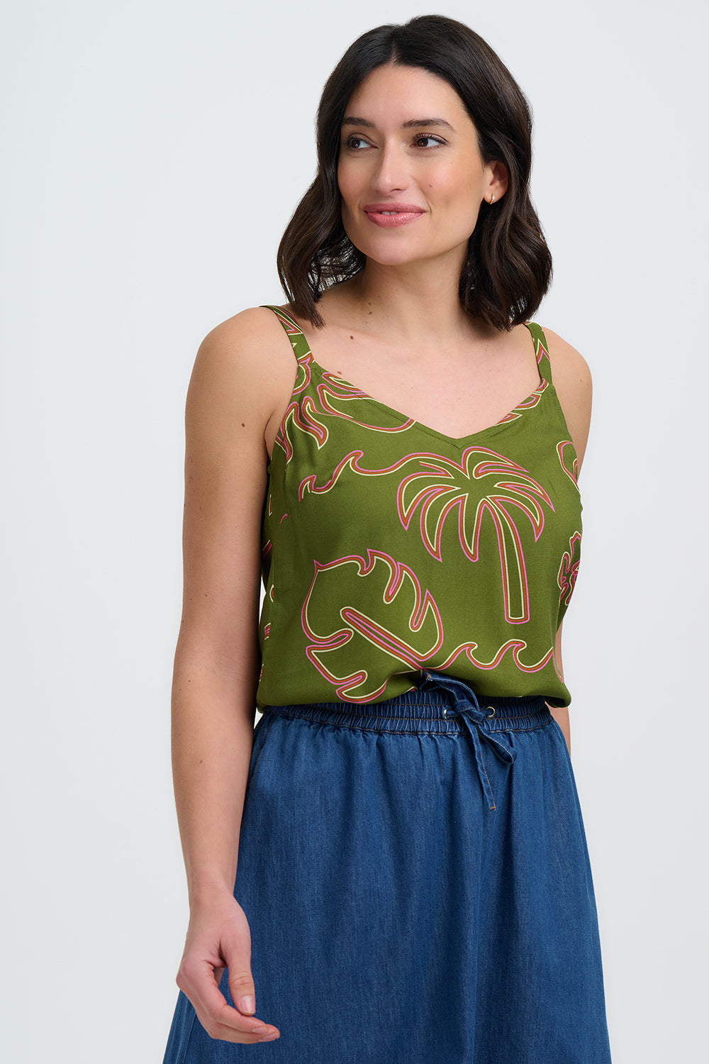 Woman wearing a green patterned top and blue skirt on a white background