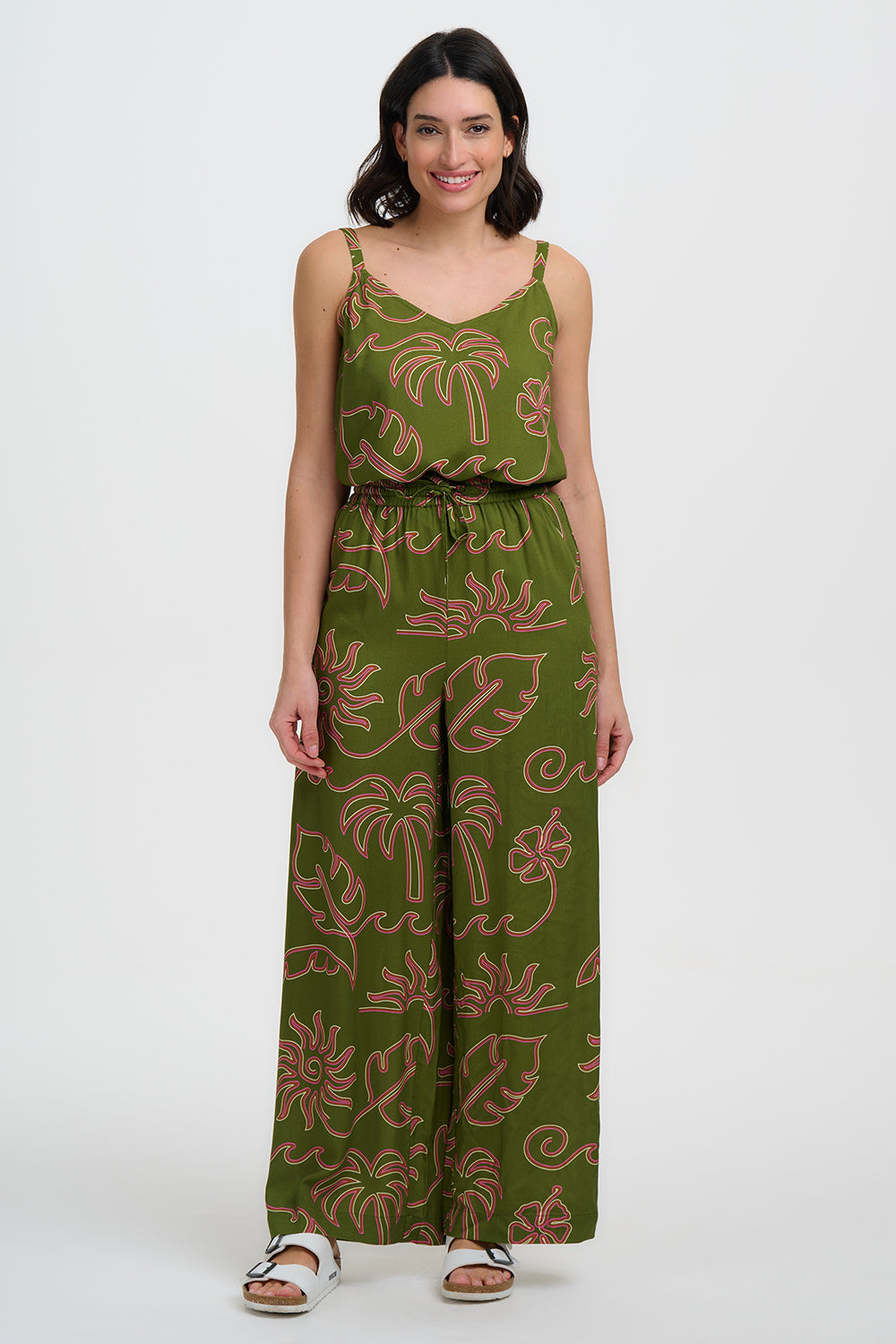Woman wearing a green floral jumpsuit on a white background