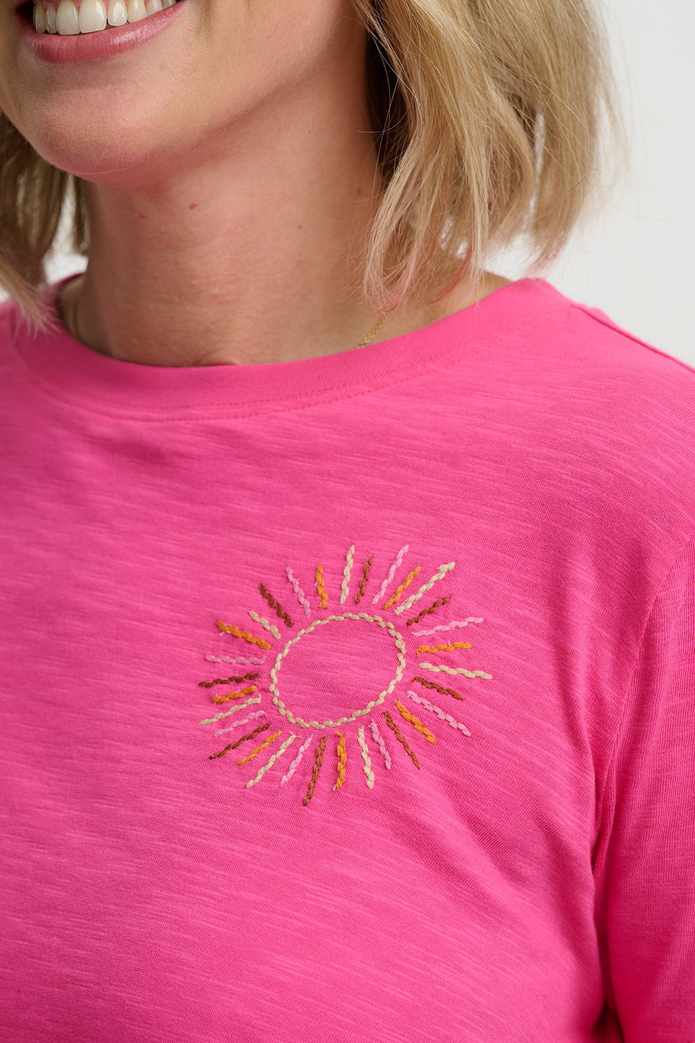 Close-up of a pink t-shirt with a sun design on a white background