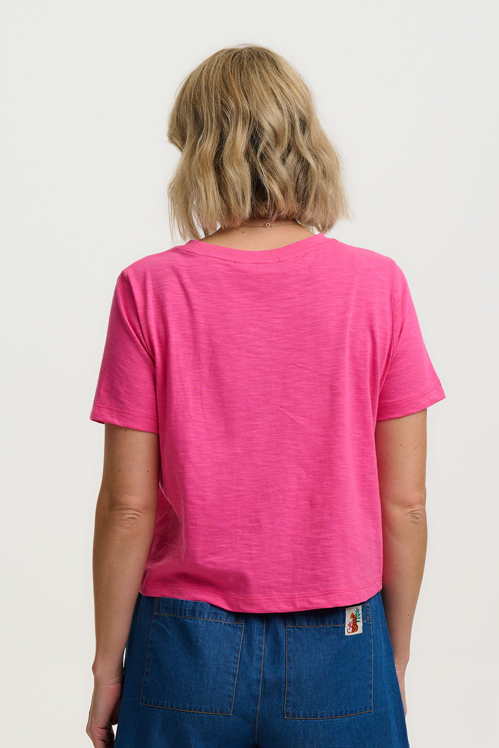 Person wearing a pink t-shirt and blue pants on a white background
