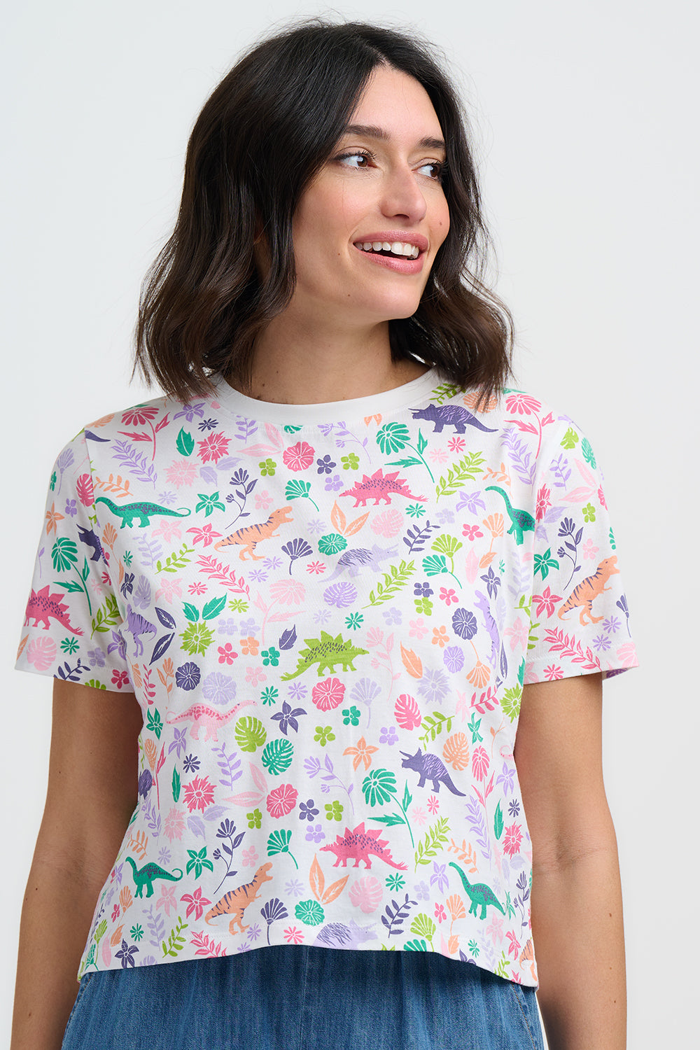 Woman wearing a colorful dinosaur pattern t-shirt against a white background