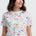 Woman wearing a colorful dinosaur pattern t-shirt against a white background