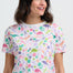Woman wearing a colorful dinosaur pattern t-shirt against a white background