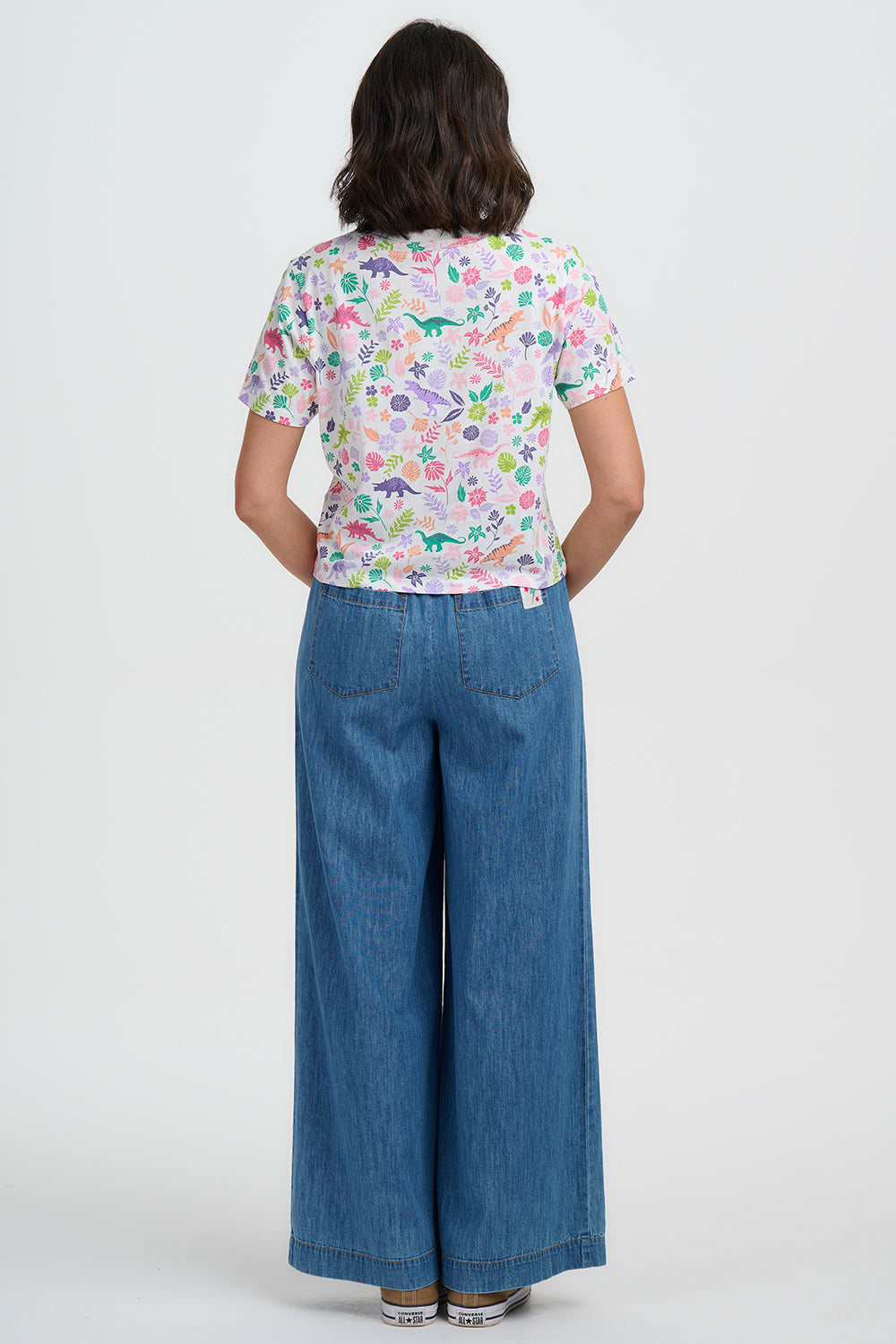 Person wearing a colorful patterned shirt and blue jeans on a white background