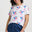 Woman wearing a white t-shirt with colorful parrot patterns and blue pants on a plain background