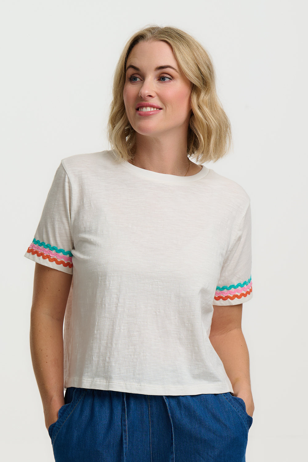 Woman wearing a white t-shirt with colorful sleeves against a plain background
