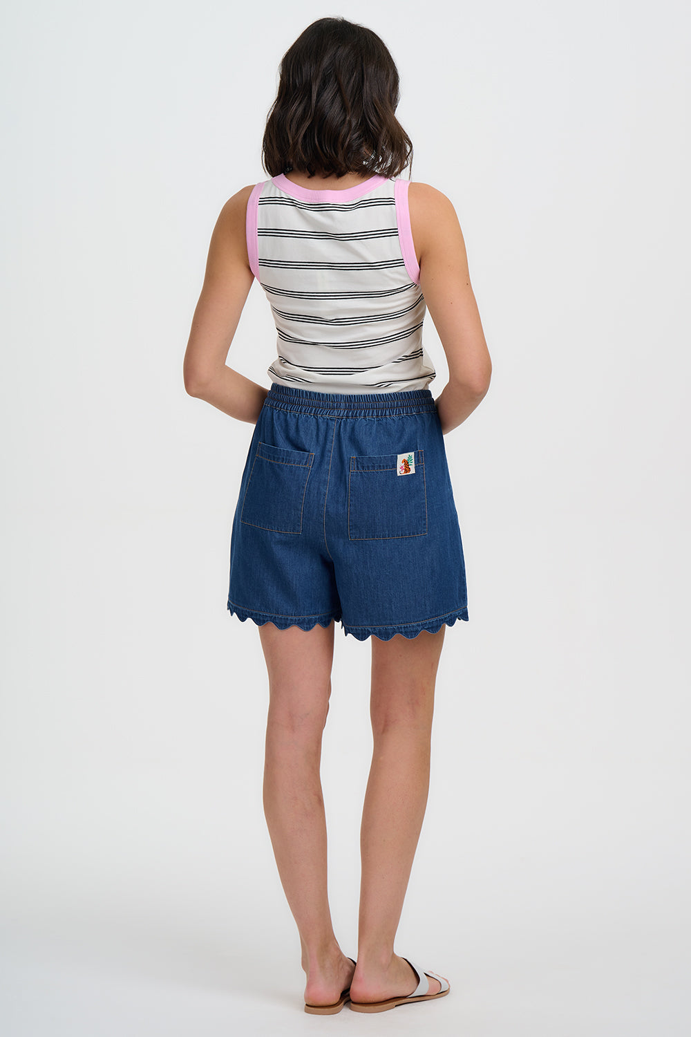 Person wearing a striped tank top and blue denim shorts on a white background