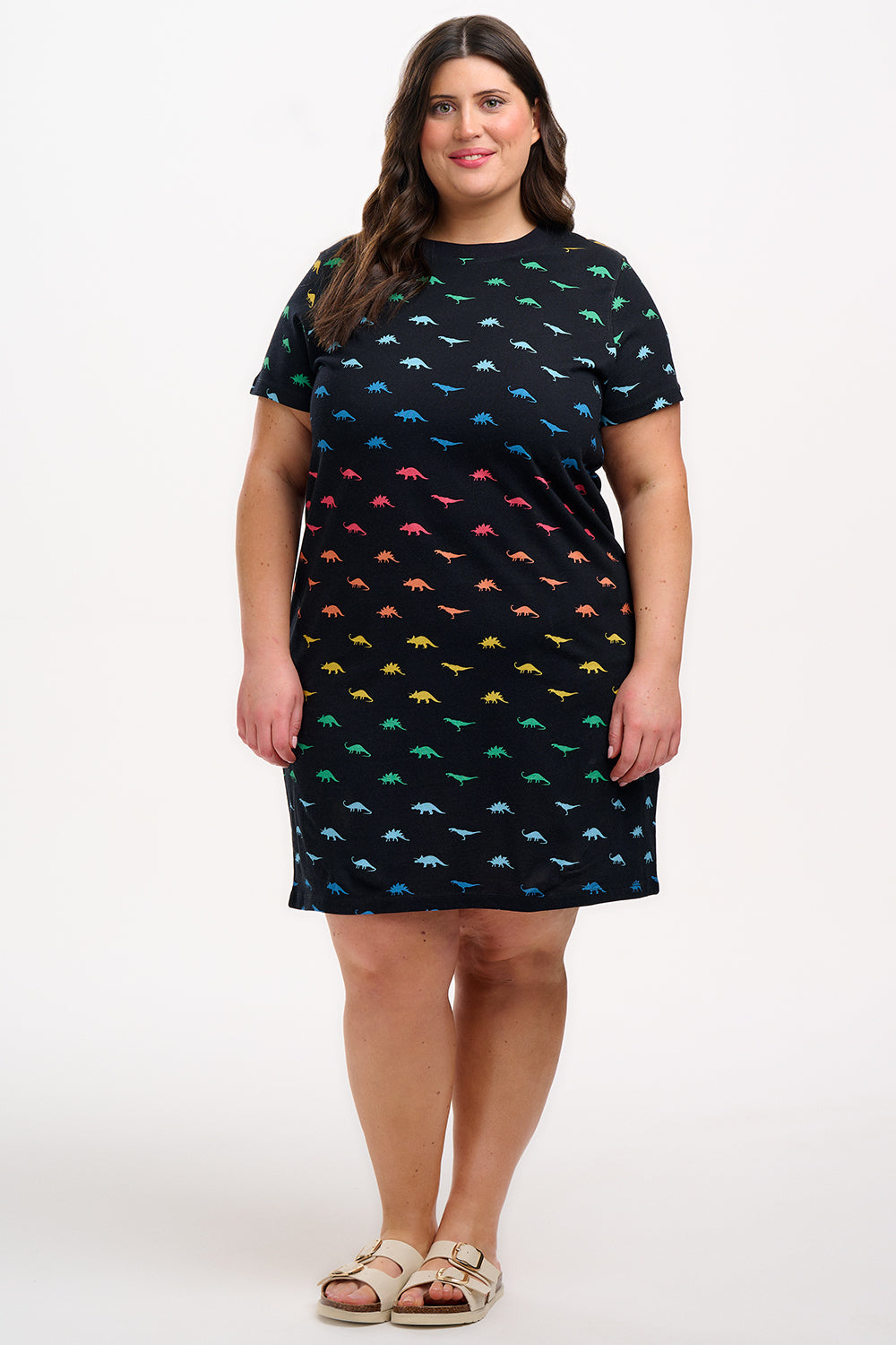 A woman wearing a black dress with colourful dinosaur pattern on a white background