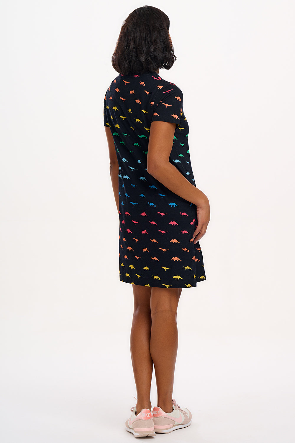 A woman wearing a black dress with colourful dinosaur pattern on a white background