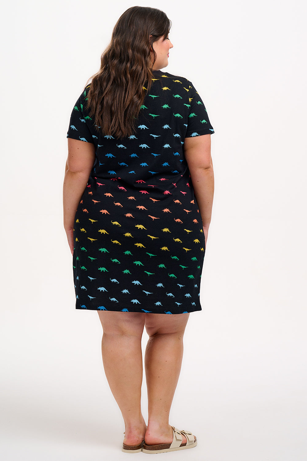 A woman wearing a black dress with colourful dinosaur pattern on a white background