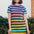 A model wearing a knee-length t-shirt dress with horizontal stripes in green and various other colors.