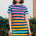 A model wearing a knee-length t-shirt dress with horizontal stripes in green and various other colors.