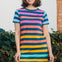 A model wearing a knee-length t-shirt dress with horizontal stripes in green and various other colors.