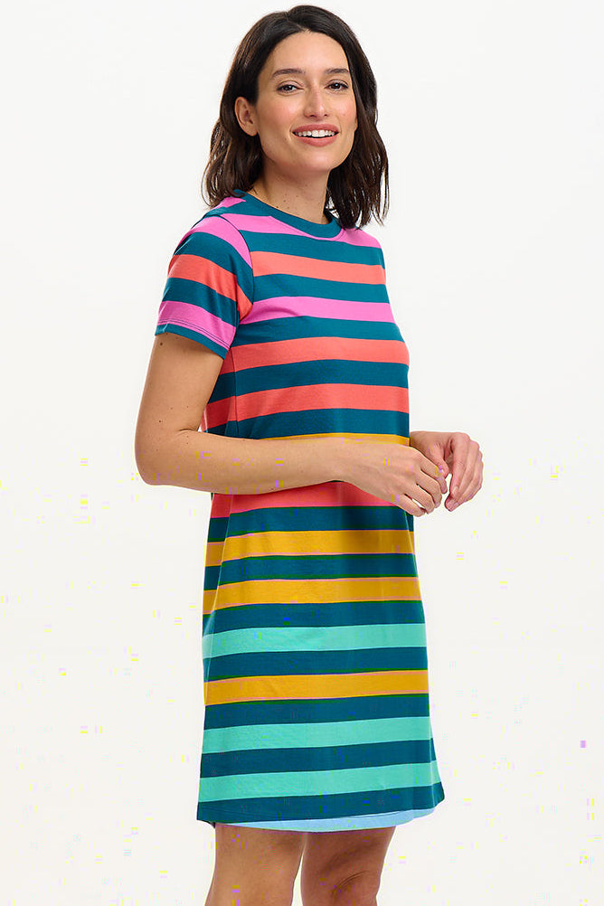 A model wearing a knee-length T-shirt dress with a colorful striped pattern in green, orange, pink, and aqua, paired with short sleeves and a round neckline.