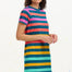 A model wearing a knee-length T-shirt dress with a colorful striped pattern in green, orange, pink, and aqua, paired with short sleeves and a round neckline.