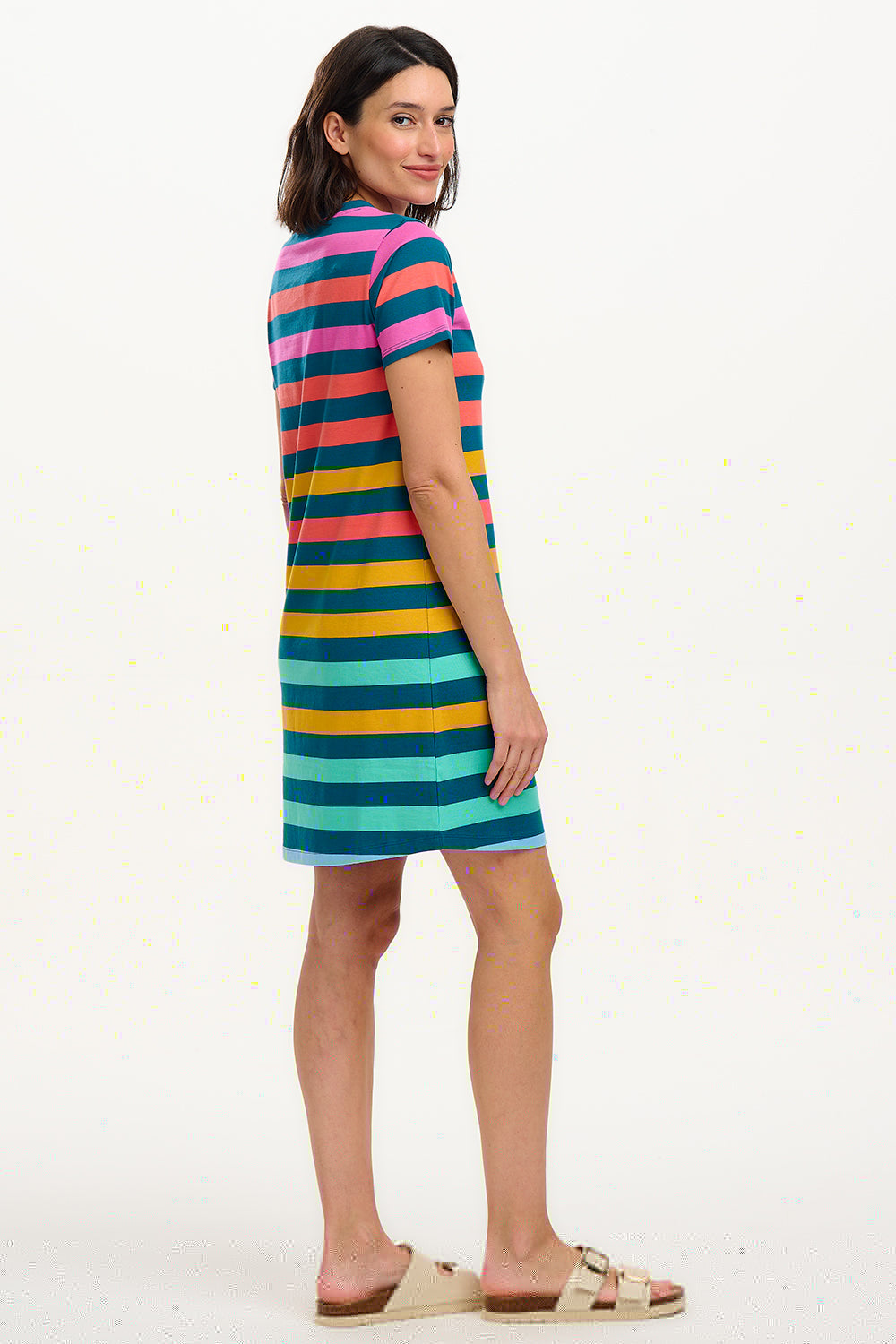 A model wearing a knee-length T-shirt dress with a colorful striped pattern in green, orange, pink, and aqua, paired with short sleeves and a round neckline.