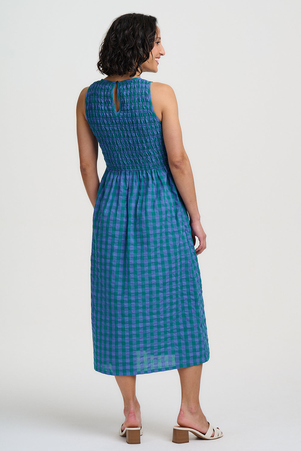 Woman wearing a blue checkered dress against a white background