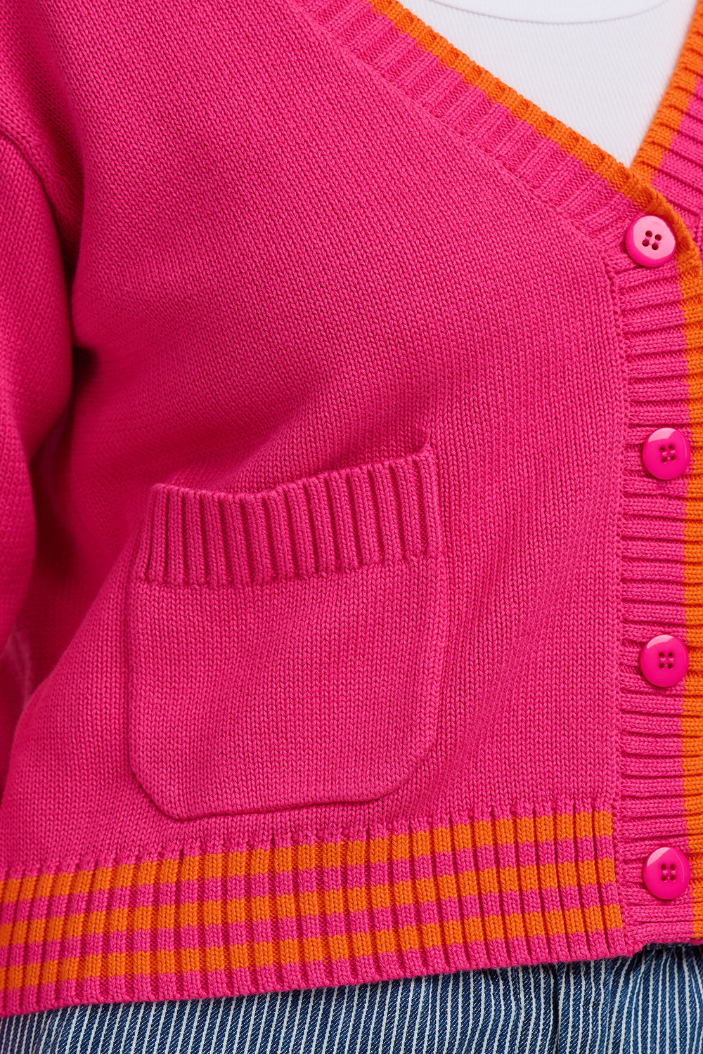 Close-up of a pink cardigan with orange trim and buttons.