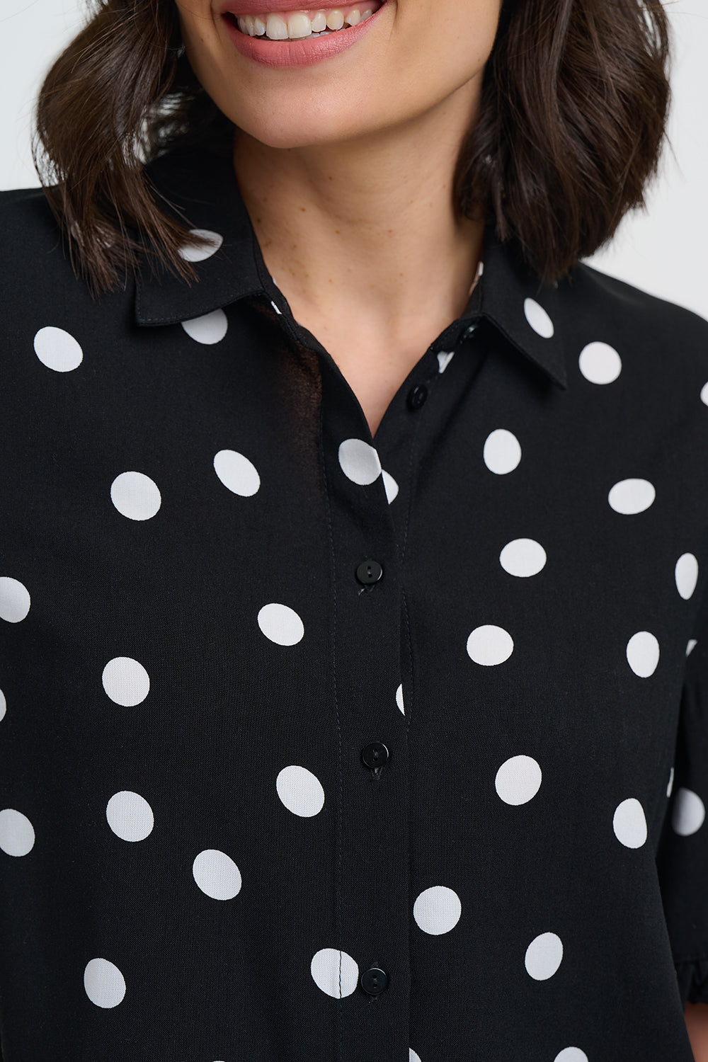 Black shirt with white polka dots worn by a person