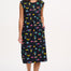 A model wearing a black midi dress with a colorful animal and floral print, standing against a white background.