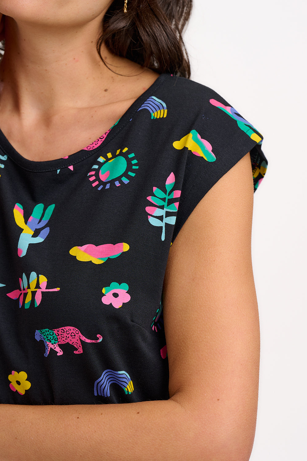 A model wearing a black midi dress with a colorful animal and floral print, standing against a white background.